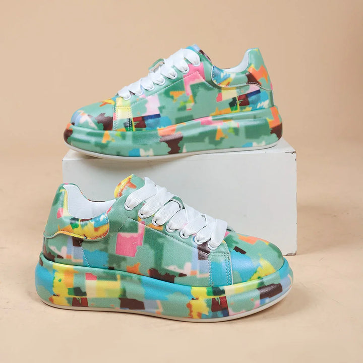 Colorful green sneakers with abstract multicolor pattern and white laces on beige background