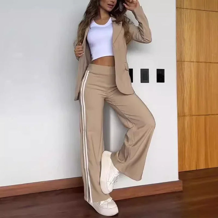 Woman wearing beige wide-leg pants with white side stripes, matching blazer, white crop top, and white sneakers