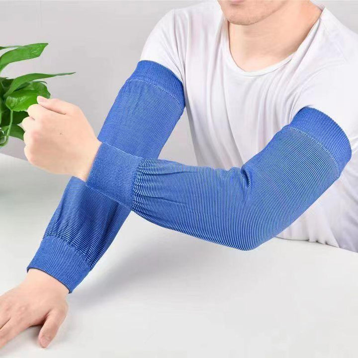 Man wearing blue striped arm sleeves over white shirt sitting at white table with a green plant nearby