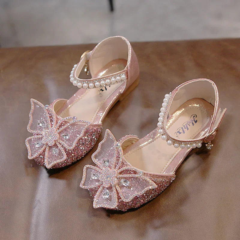 Pink glitter girls' shoes with pearl ankle straps and large butterfly decorations on toes