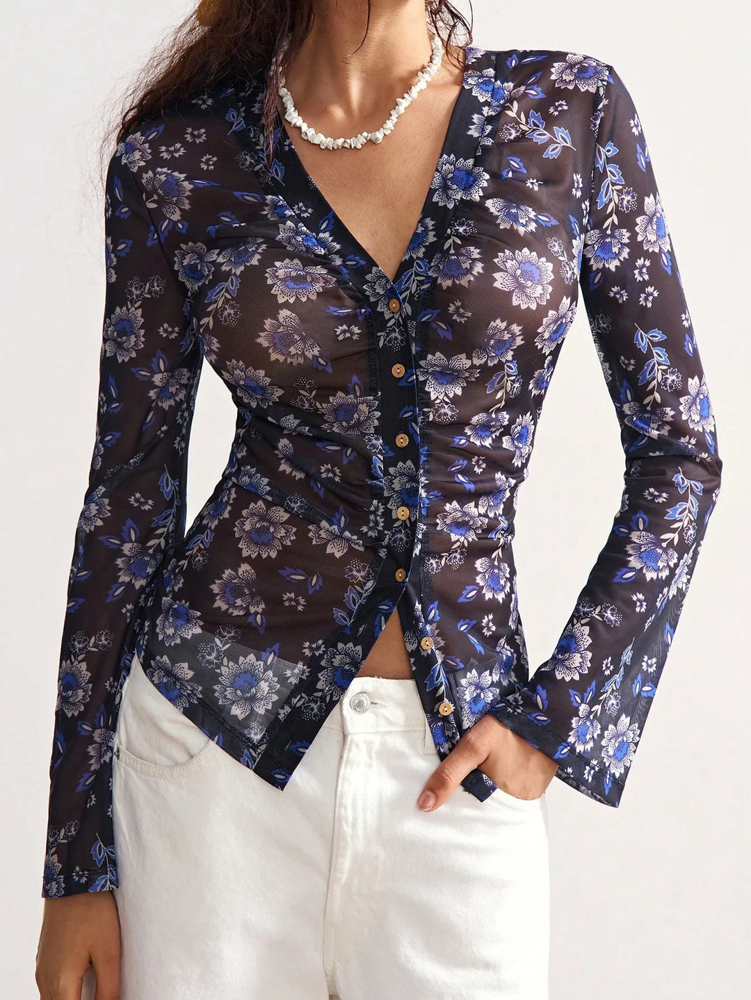 woman wearing black sheer floral mesh blouse with blue flowers and white pants