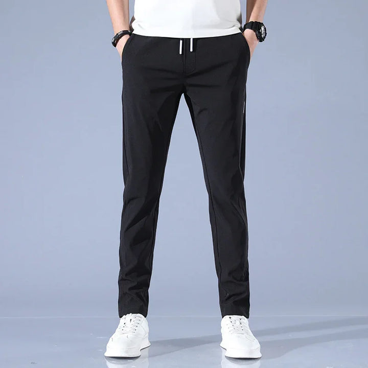 Front view of man wearing black slim fit pants with white drawstrings and white sneakers
