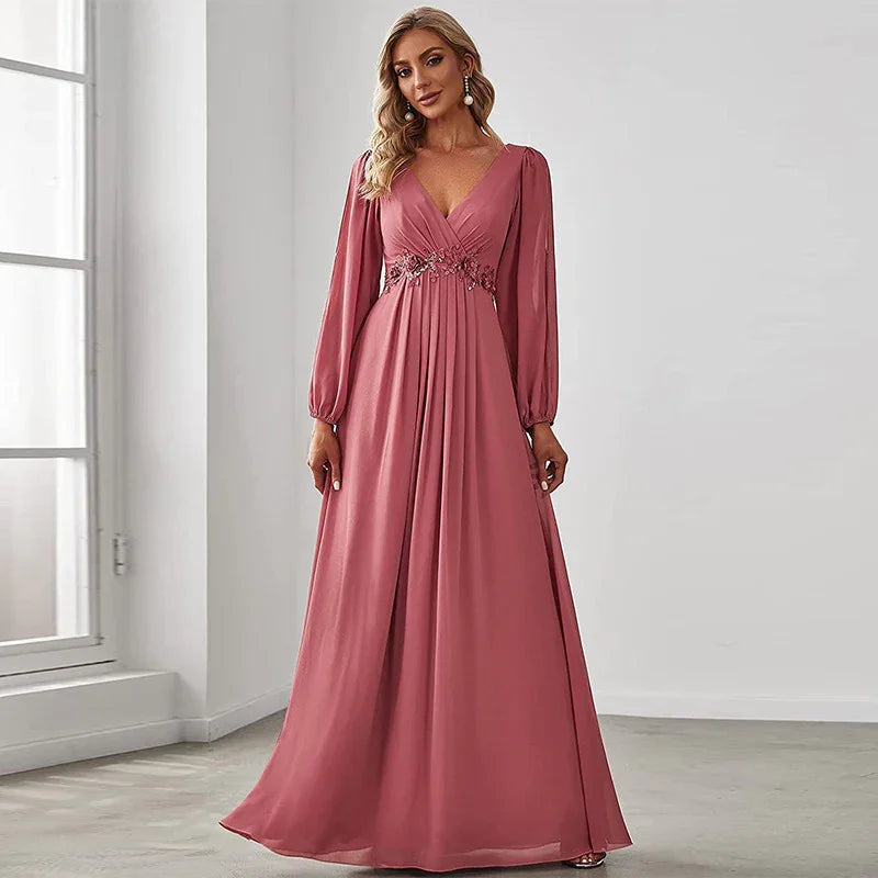 Woman wearing a long-sleeve dusty rose formal gown with V-neck and floral waist embellishment in bright room