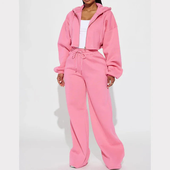 Woman wearing pink cropped hoodie and matching wide-leg sweatpants with white tank top