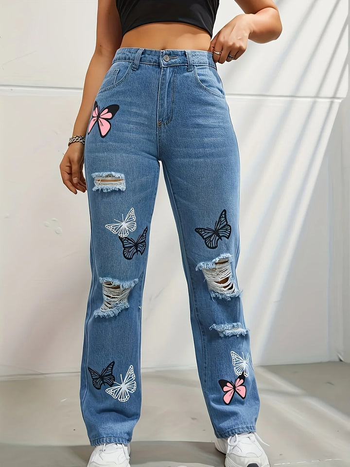 Woman wearing high-waisted ripped blue jeans with white, black, and pink butterfly prints