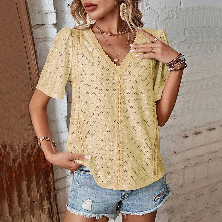 Woman wearing yellow eyelet V-neck blouse with short puff sleeves and distressed denim shorts