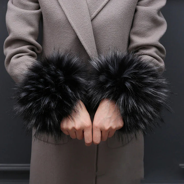 Person wearing a beige coat with large, fluffy black faux fur cuffs on sleeves