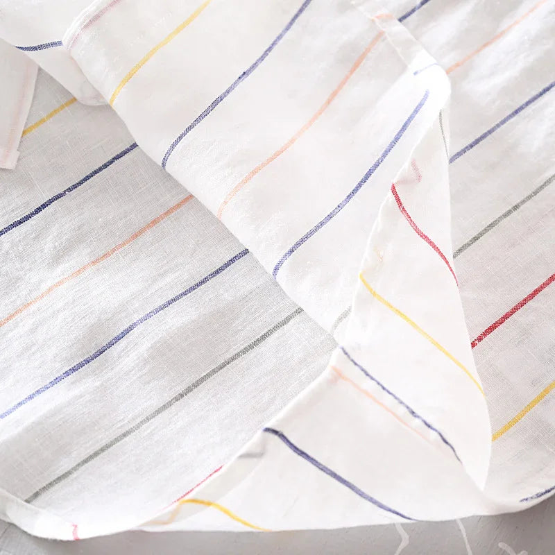 White fabric with colorful thin vertical stripes in red, yellow, blue, orange, and gray on a light surface