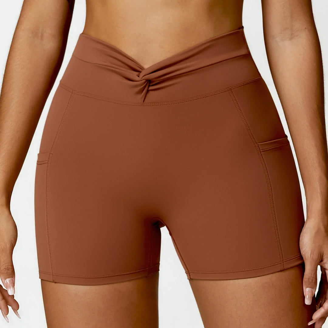 Woman wearing high-waisted brown workout shorts with front twist detail and side pockets