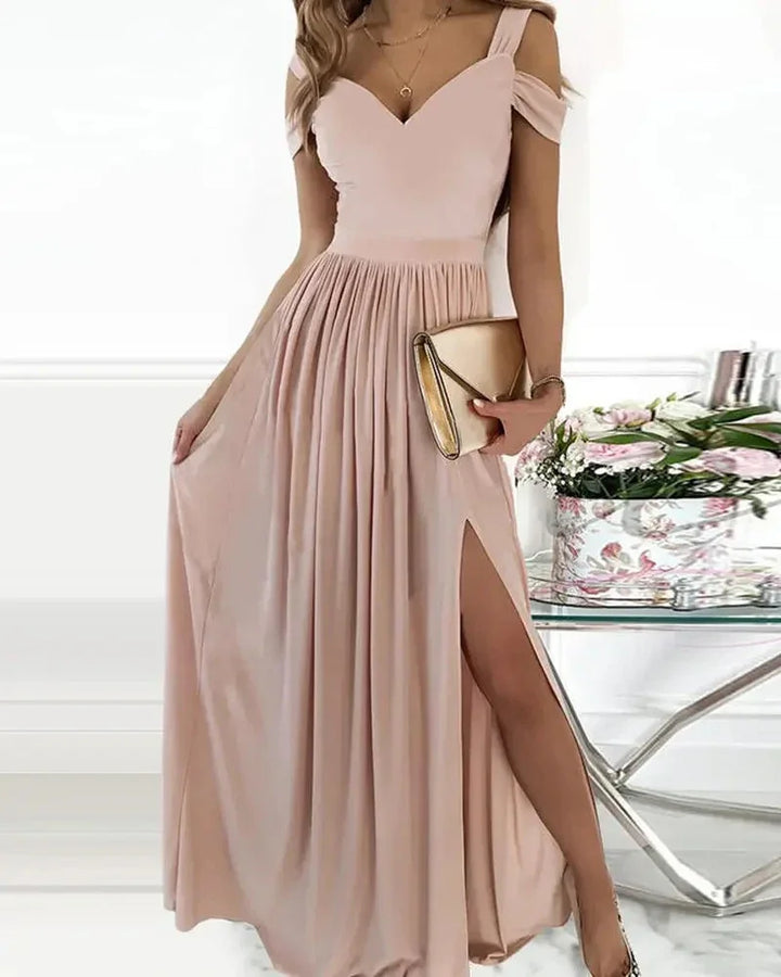 Elegant woman wearing a blush pink off-shoulder evening gown with thigh slit and holding gold clutch