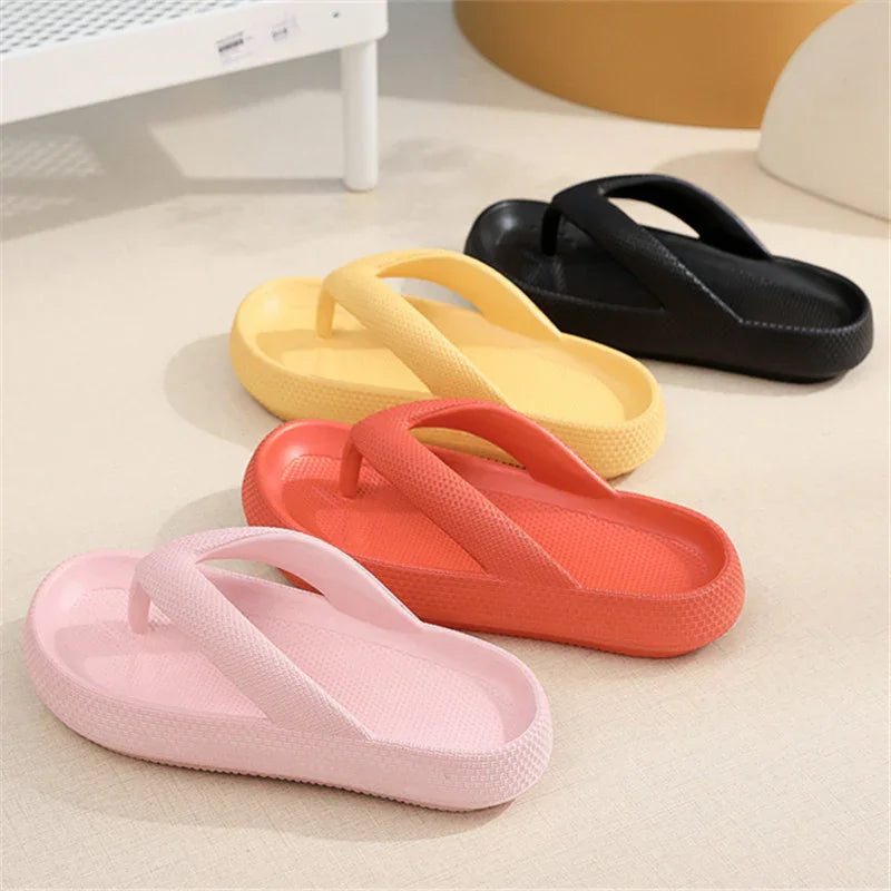 Four pairs of textured foam flip flops in pink, orange, yellow, and black on a beige floor
