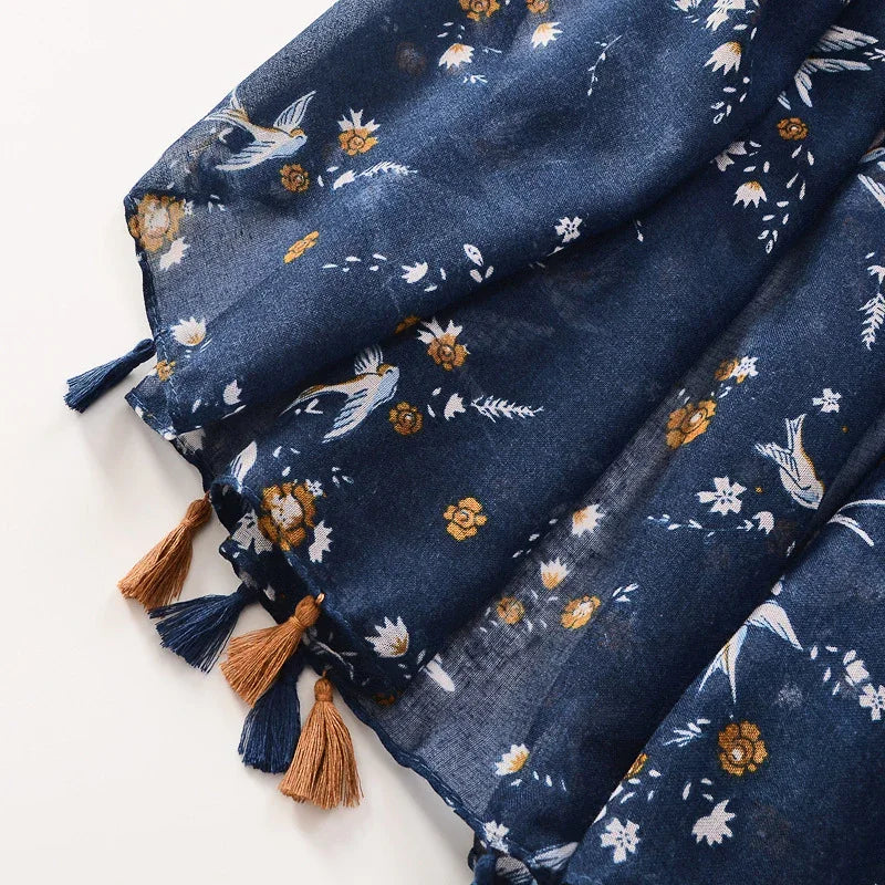 Navy blue scarf with floral and bird print, featuring brown and blue tassels on edges