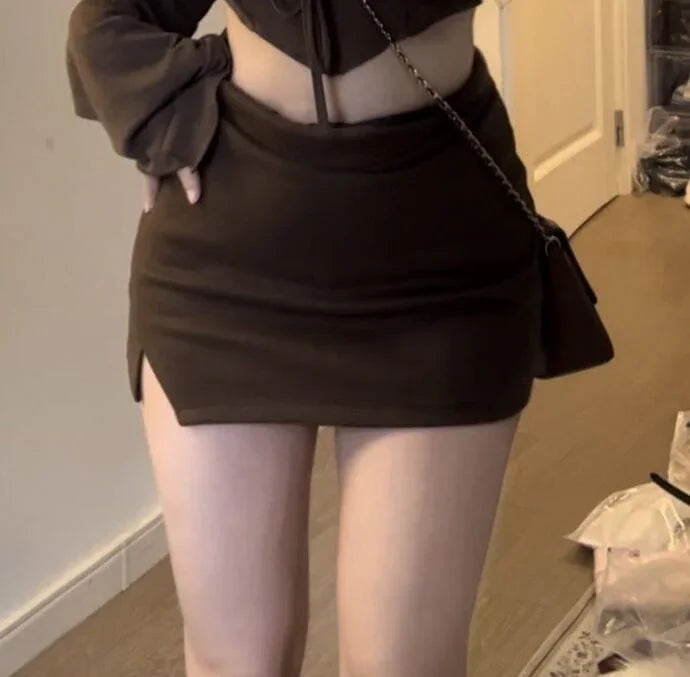 Woman wearing a black mini skirt with a small side slit and matching black top, indoors with wooden flooring