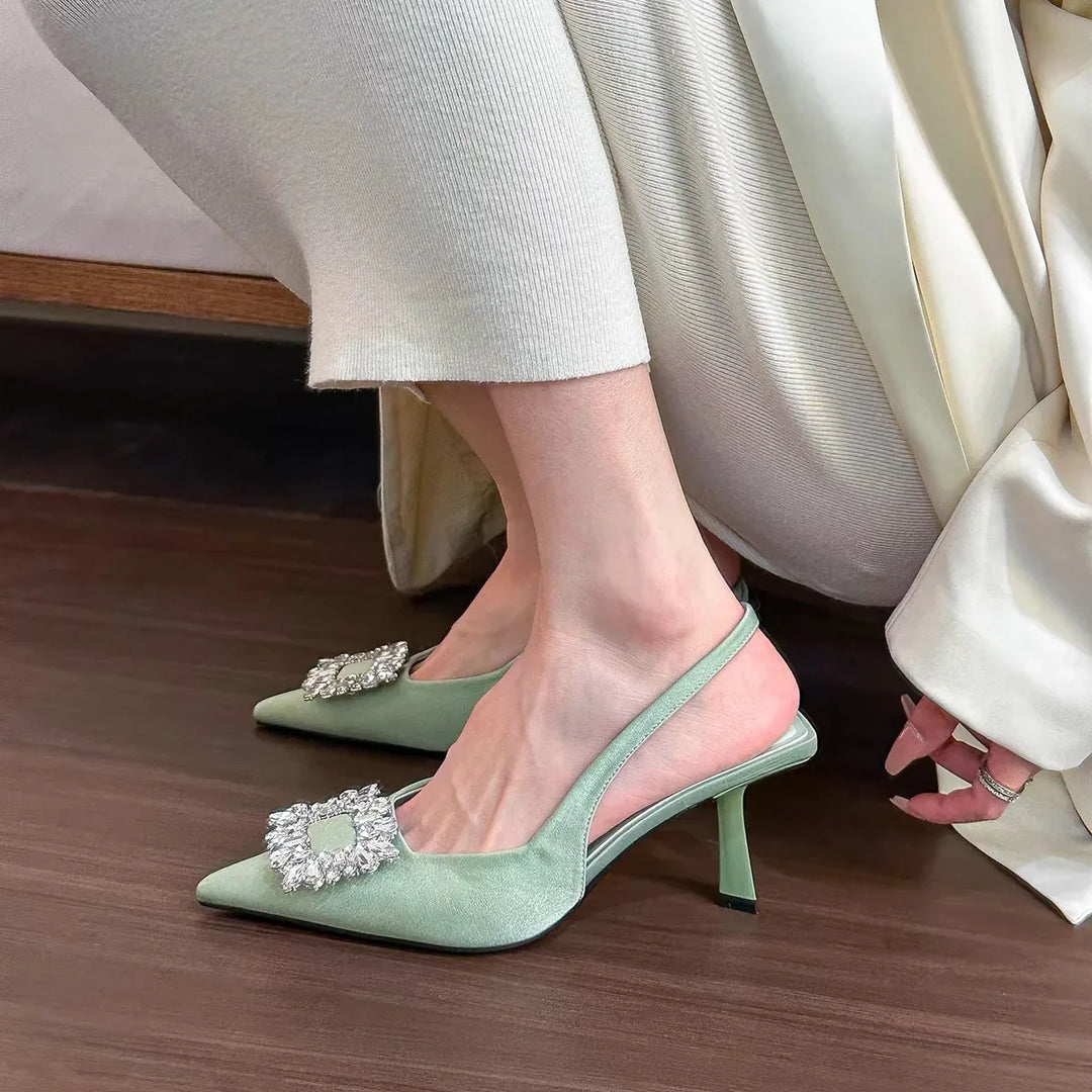 Woman wearing mint green suede slingback heels with crystal buckle on wooden floor