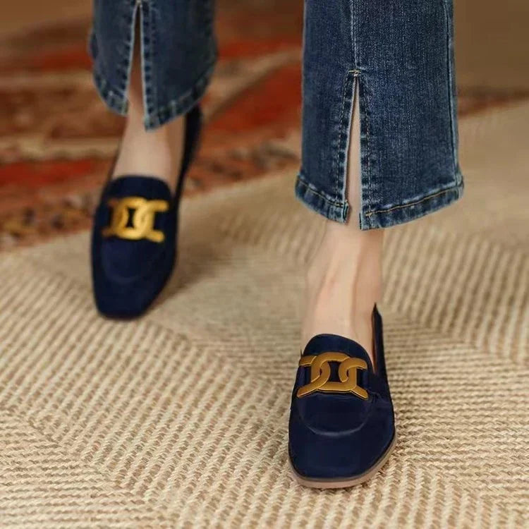 Navy blue suede loafers with gold chain detail worn with cropped split hem jeans on textured rug