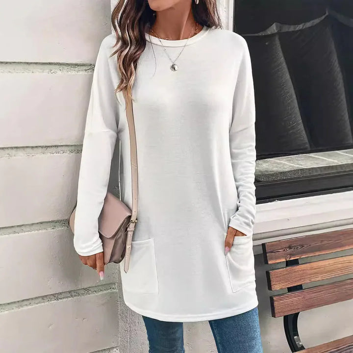 Woman wearing casual long sleeve white tunic top with pockets and carrying beige crossbody bag