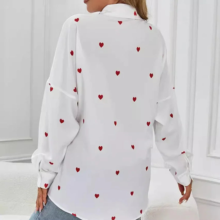 Back view of woman wearing white blouse with red heart prints in a modern white room