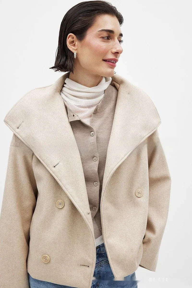Woman wearing beige wool coat with large lapels, cream turtleneck, and buttoned beige cardigan