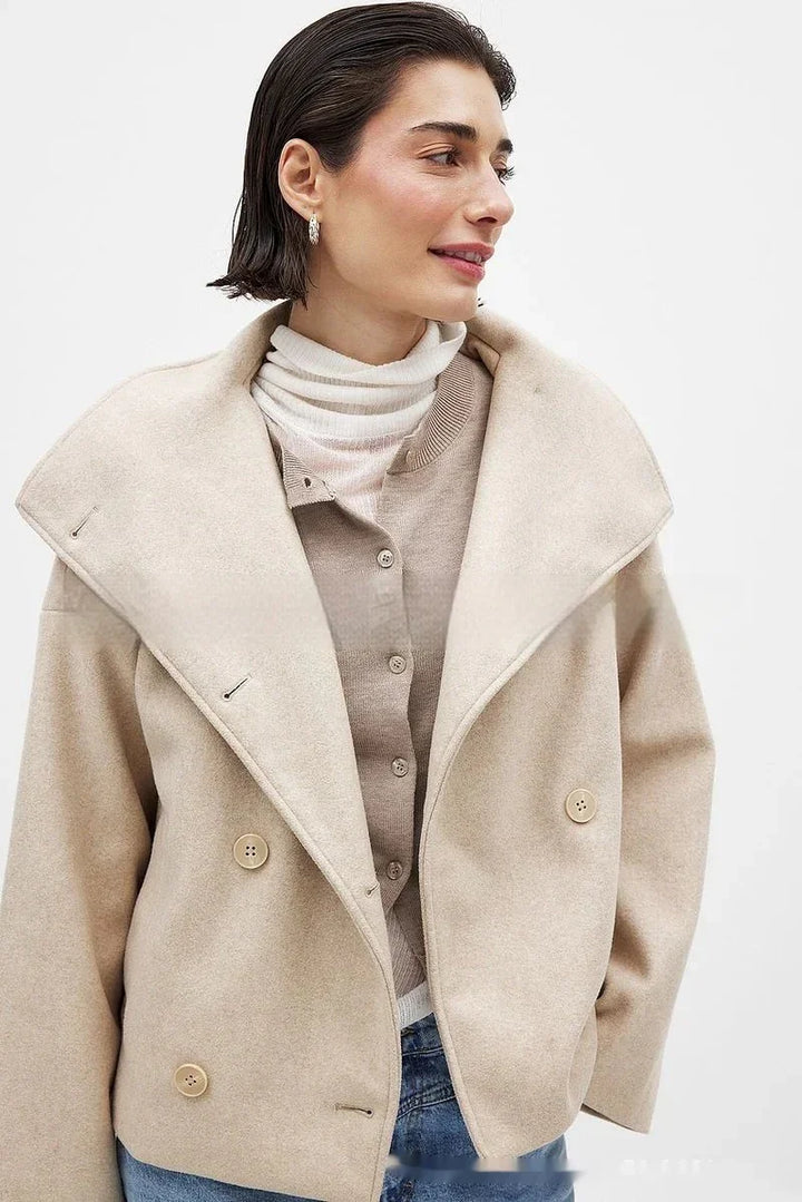 Woman wearing beige wool coat with large lapels, cream turtleneck, and buttoned beige cardigan