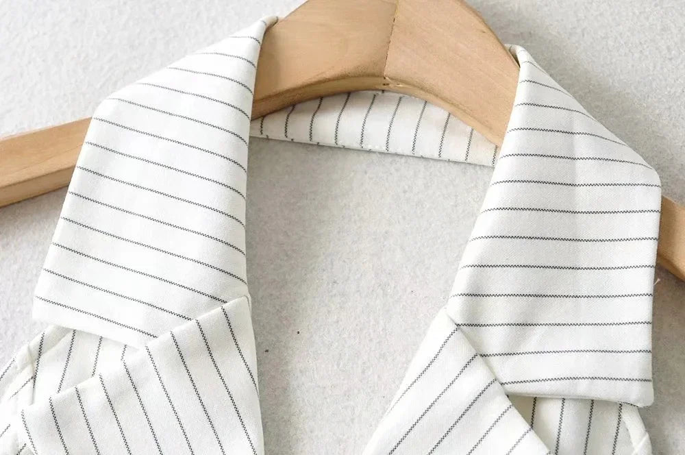 Close-up of white collared shirt with thin black stripes hanging on wooden hanger