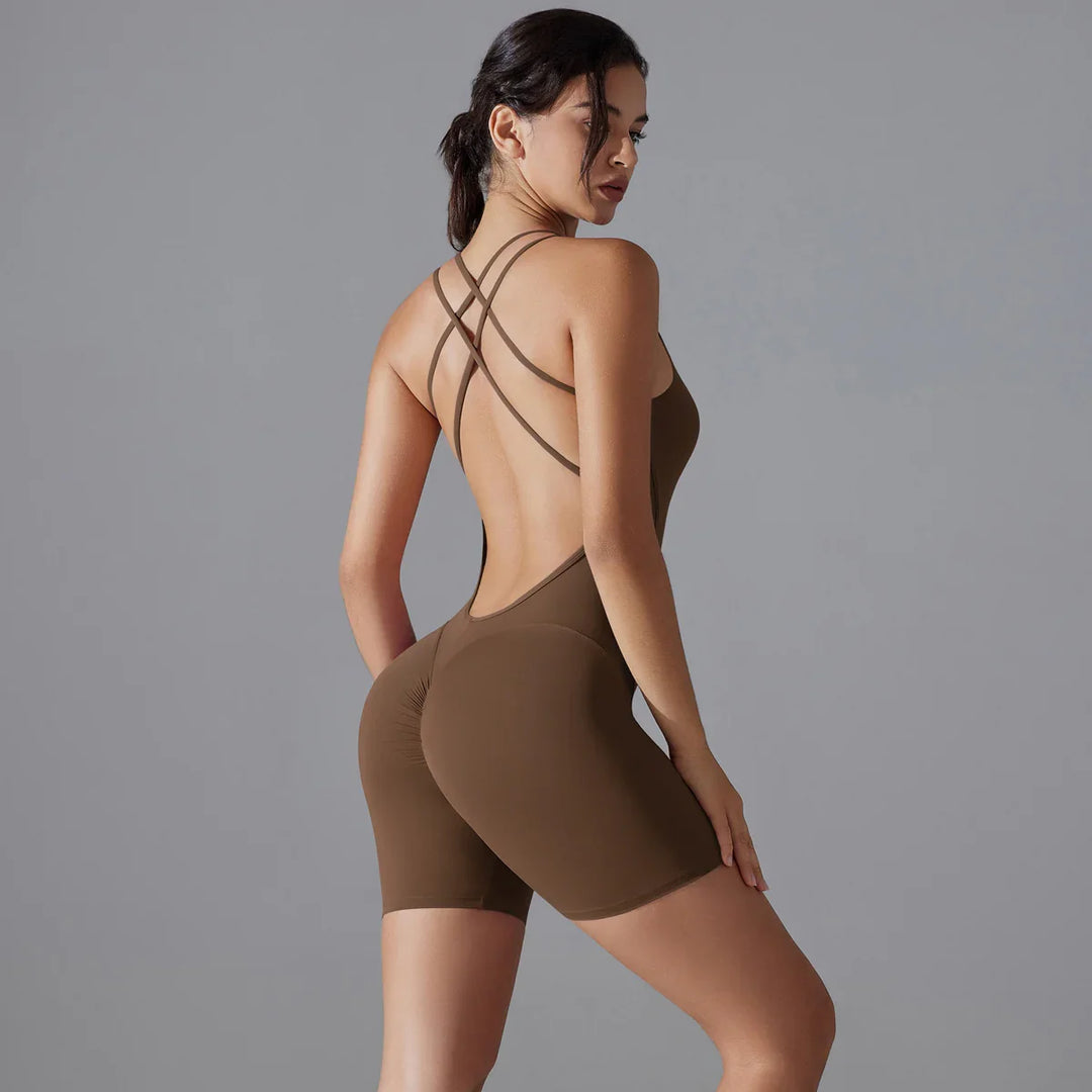 Woman wearing brown seamless open-back workout bodysuit with crisscross straps against gray background
