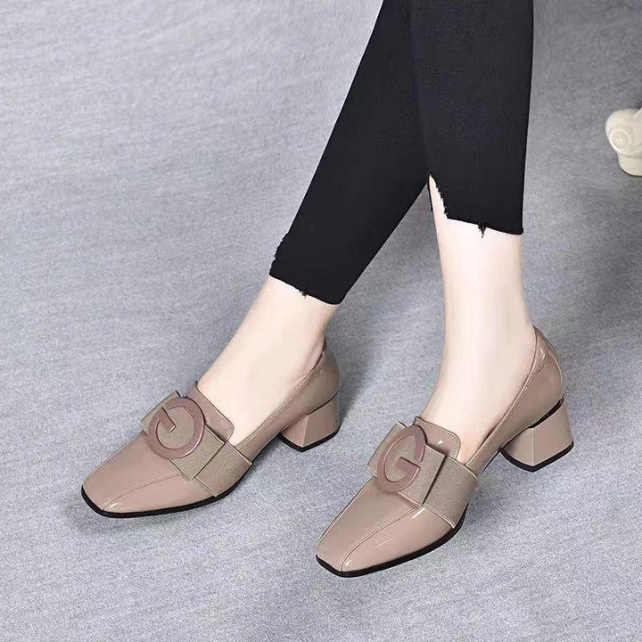 Beige block heel women's shoes with wide strap and decorative letter detail worn with black cropped pants