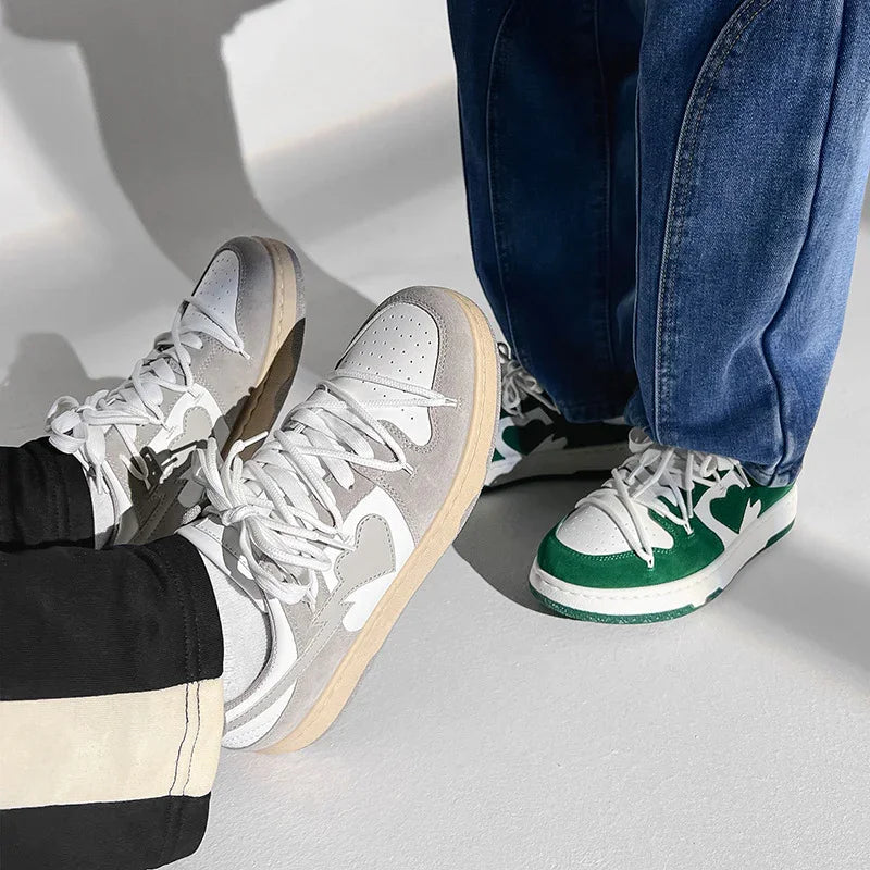 Close-up of two pairs of stylish sneakers in white with gray and green accents on light floor
