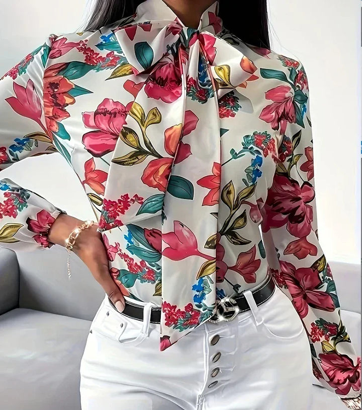 Woman wearing a white floral blouse with a large bow tie and white high-waisted pants