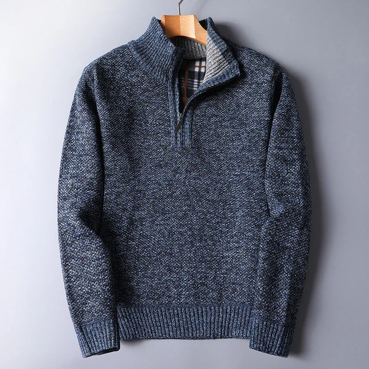 Blue textured quarter-zip men's sweater with ribbed cuffs and plaid inner collar hanging on wooden hanger