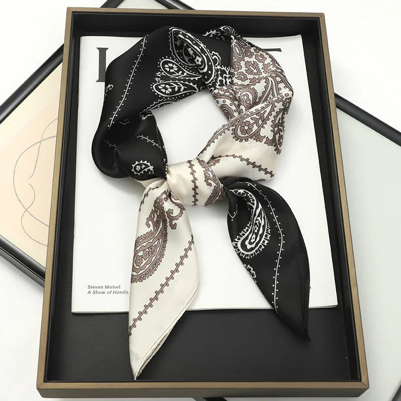 Black and white paisley silk bandana scarf neatly tied and displayed in a black tray