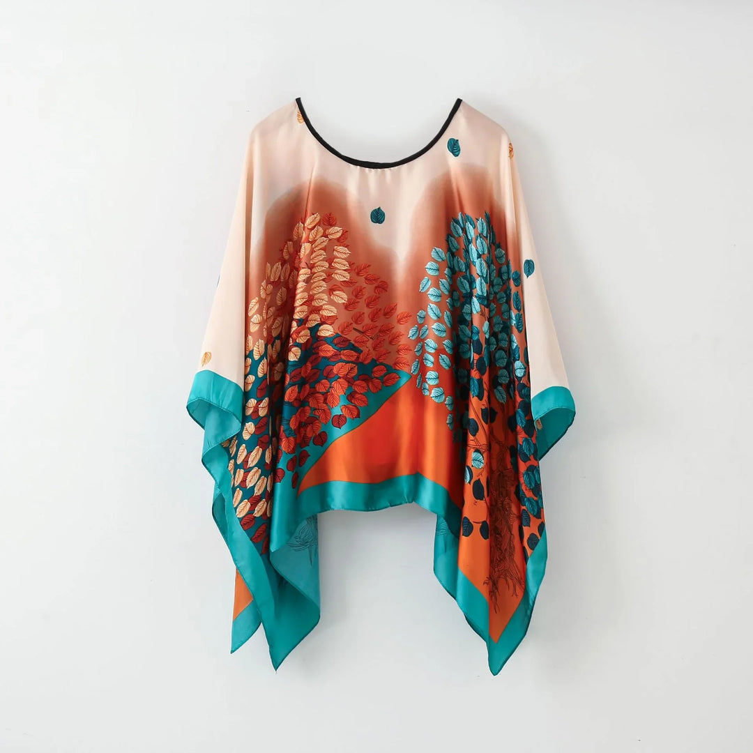 Colorful satin poncho with teal, orange, and brown leaf pattern and handkerchief hem
