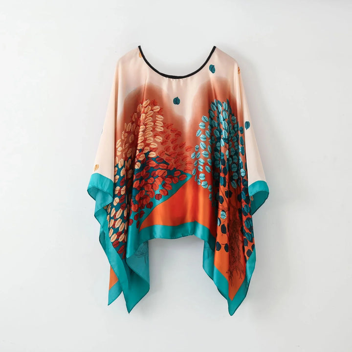 Colorful satin poncho with teal, orange, and brown leaf pattern and handkerchief hem