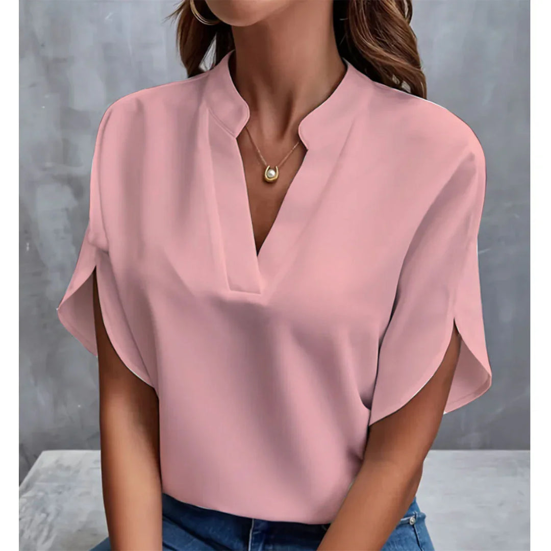 Woman wearing light pink V-neck blouse with split short sleeves and gold pendant necklace