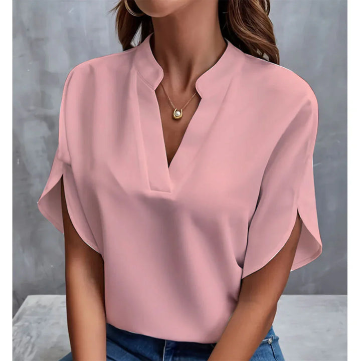Woman wearing light pink V-neck blouse with split short sleeves and gold pendant necklace