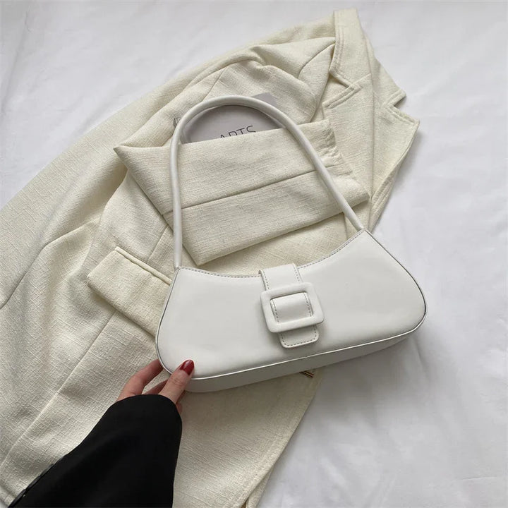 Minimalist white leather handbag with buckle on beige textured blazer background