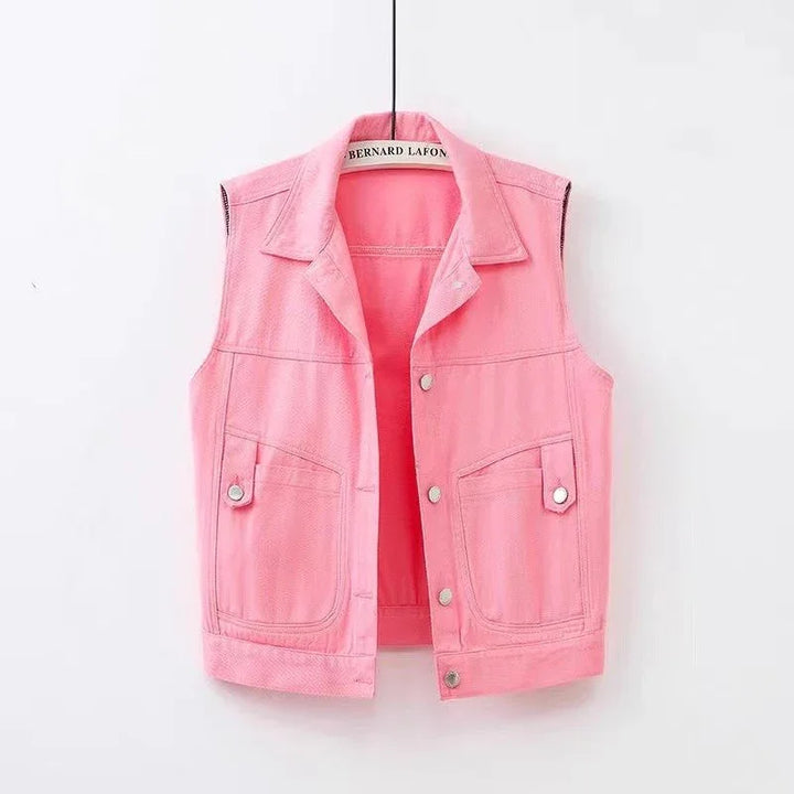 Pink sleeveless denim vest with collar and button closure hanging on white background