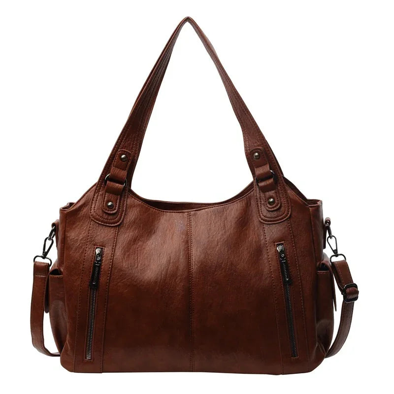 Brown leather handbag with dual handles, front zipper pockets, and detachable shoulder strap