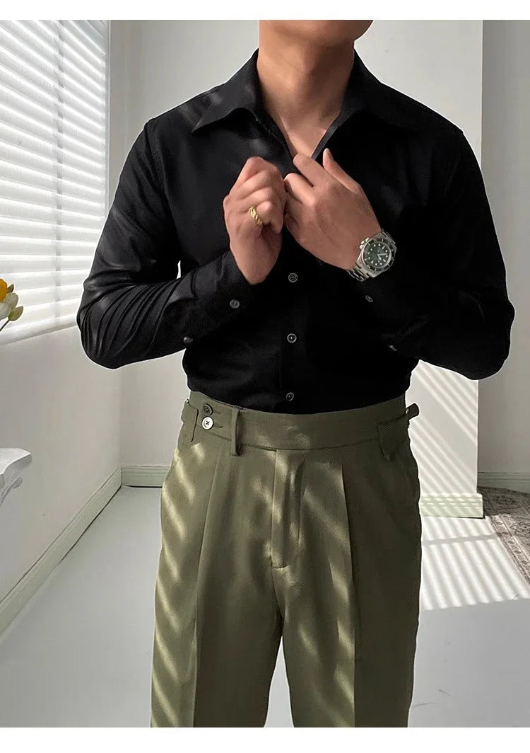 Man wearing black button-up shirt and olive green high-waisted pants in a bright room