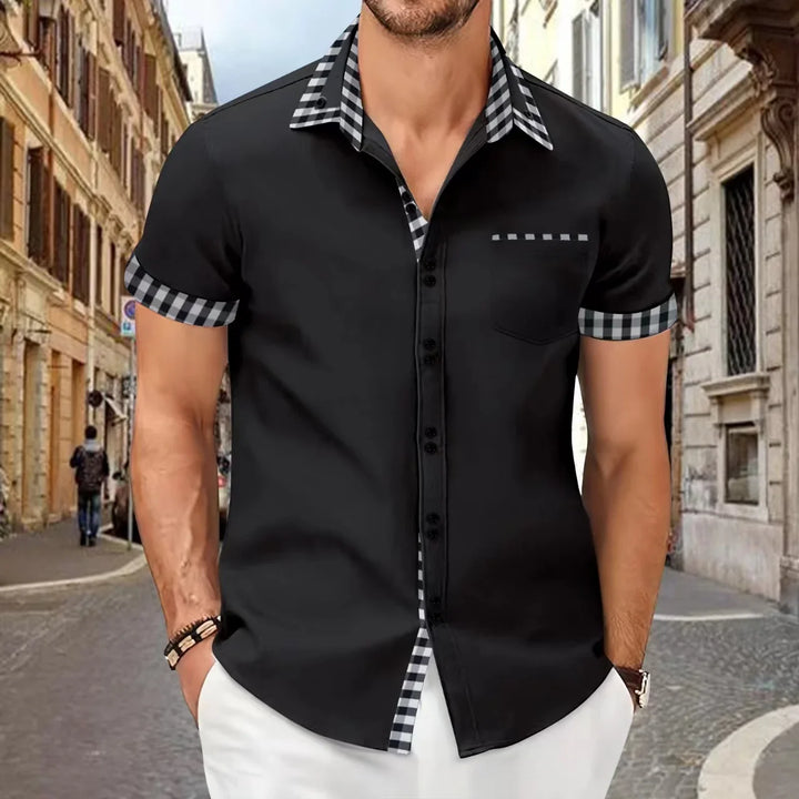 Man wearing black short-sleeve button-up shirt with black and white checkered collar and sleeve cuffs on urban street