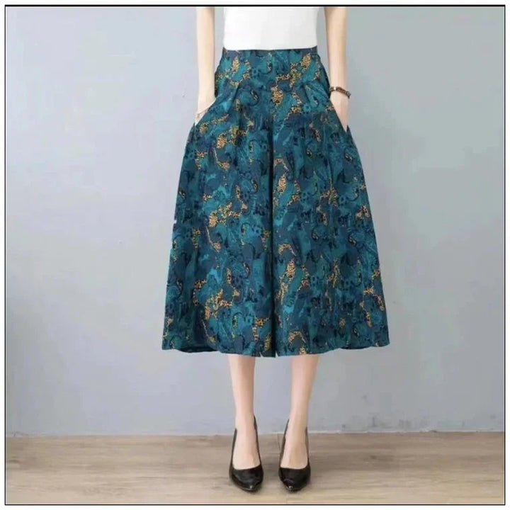 Woman wearing teal blue midi skirt with leopard print pattern and black heels on wooden floor