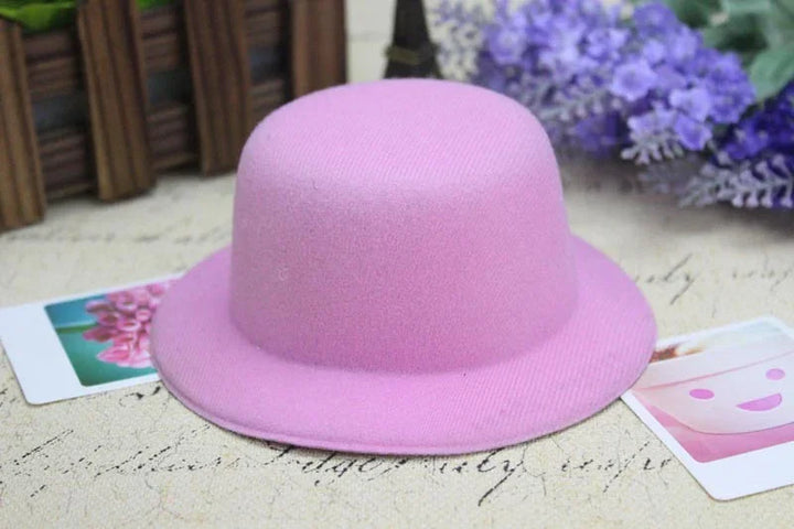 Pink wool bowler hat on vintage paper background with purple flowers and photo cards