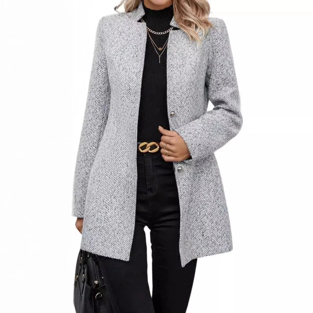Woman wearing gray herringbone blazer over black turtleneck and black jeans with gold chain belt and layered necklaces