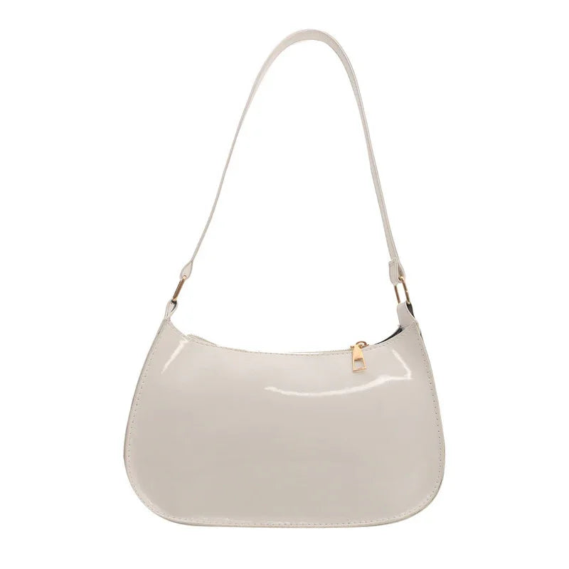 Shiny beige patent leather shoulder bag with gold zipper and strap hardware on white background