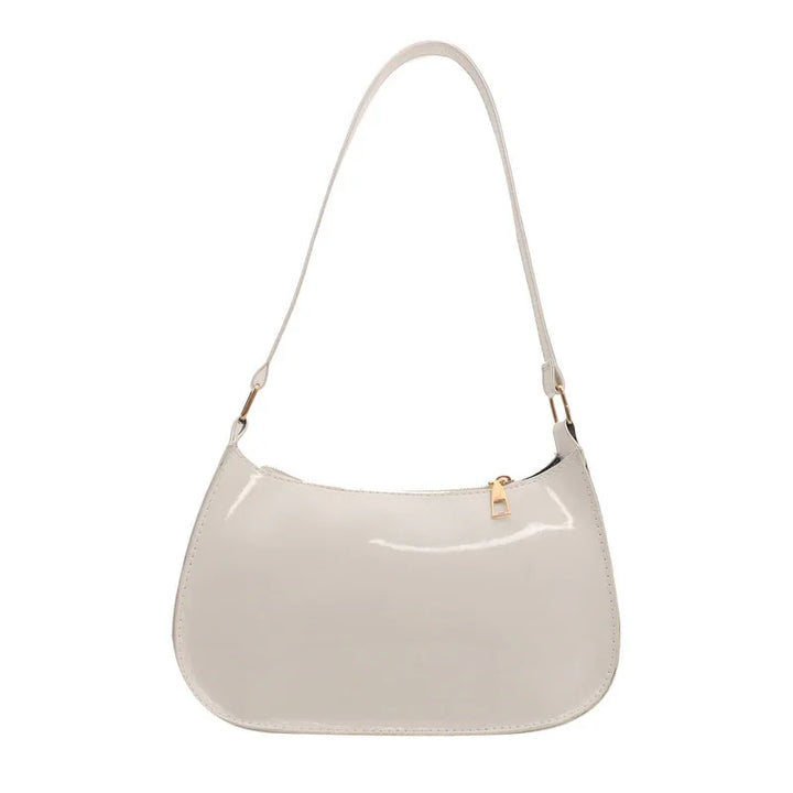 Shiny beige patent leather shoulder bag with gold zipper and strap hardware on white background
