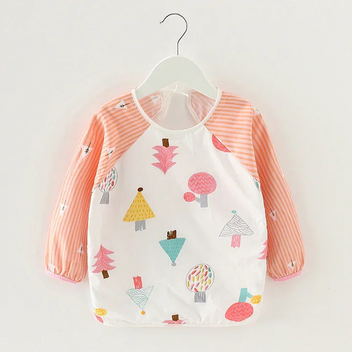 Child's long sleeve bib with pink striped sleeves and colorful cartoon tree prints on white fabric