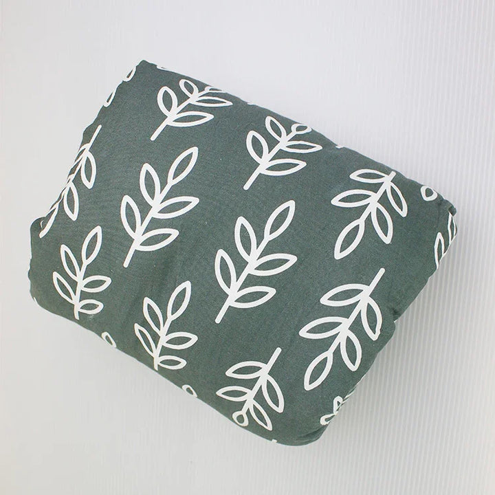 Folded green fabric with a white leaf branch pattern on a light background