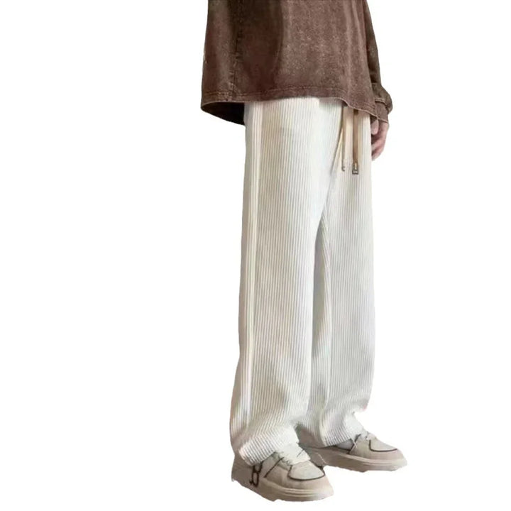 Person wearing white ribbed wide-leg pants with drawstring and beige sneakers