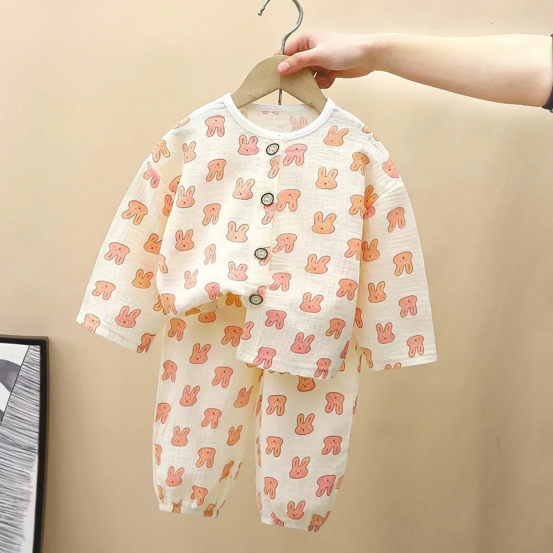 Hand holding baby pajamas with pink bunny print, long sleeves, button-up top and elastic ankle pants