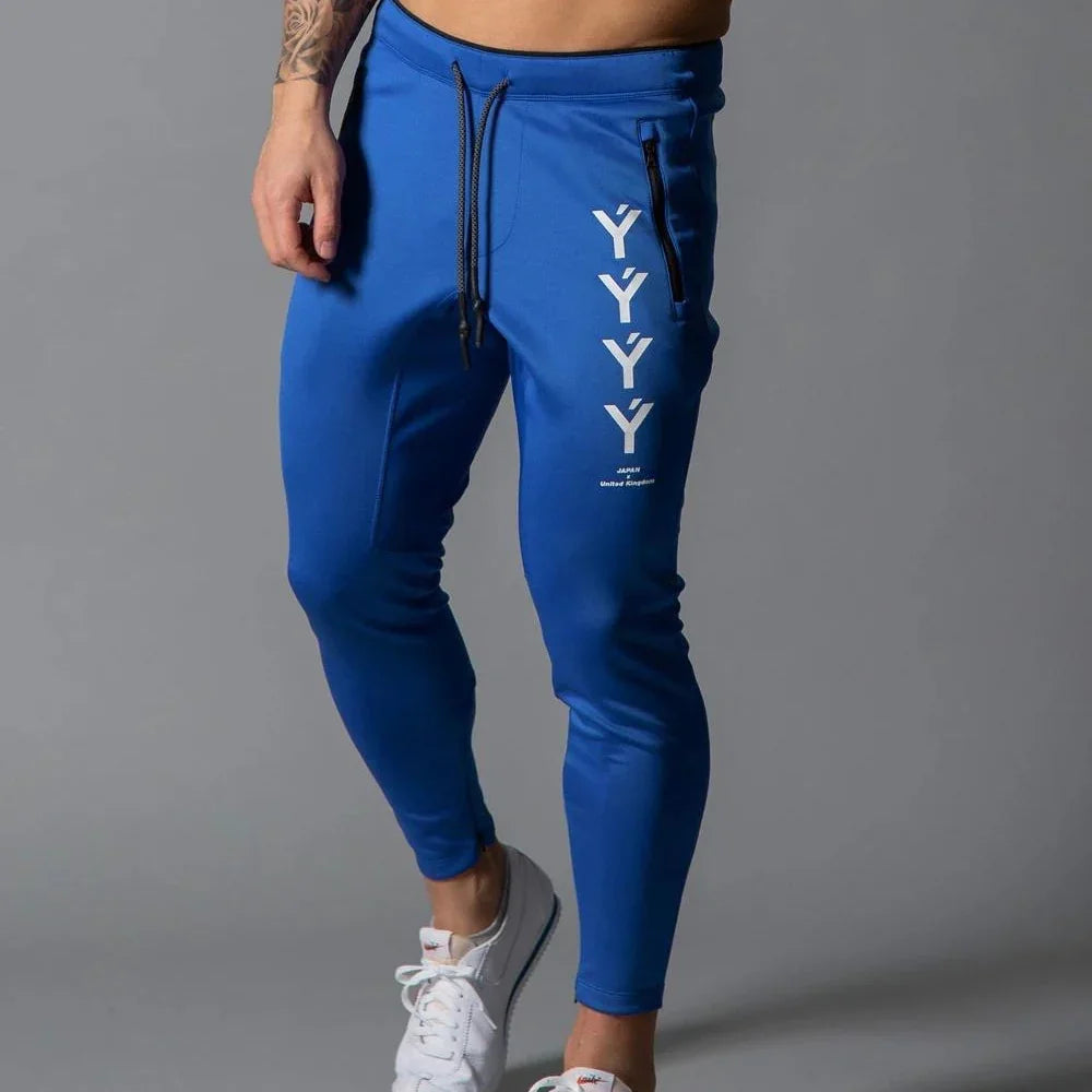 Man wearing blue joggers with vertical white Y letters and zip pocket, paired with white sneakers