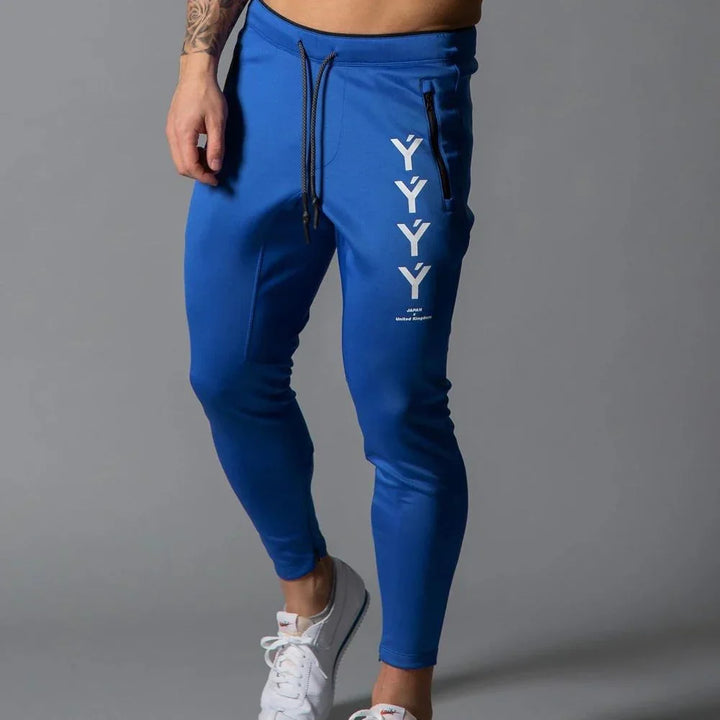 Man wearing blue joggers with vertical white Y letters and zip pocket, paired with white sneakers